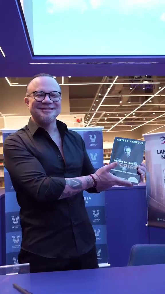 Valter Pinheiro segurando seu livro na mesa de autógrafos da Livraria da Vila